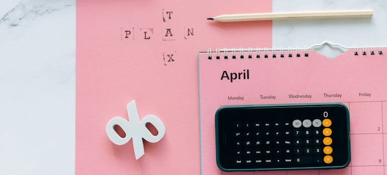 Calendar and calculator on a desk to help with budget planning when learning what to expect when moving to a different state.