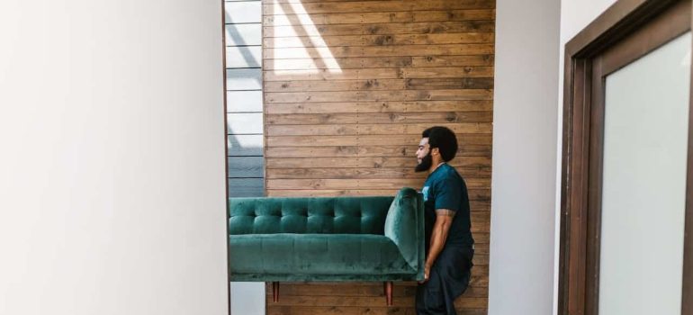 man carrying a couch and trying to survive moving in winter