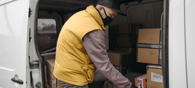 a man unloading boxes from a van knowing that shuttle services overcome