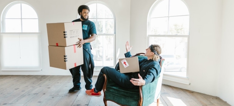professional movers, one sitting, the other standing and both carrying boxes