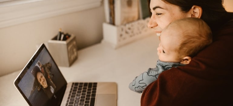 a woman holding a baby and using a laptop
