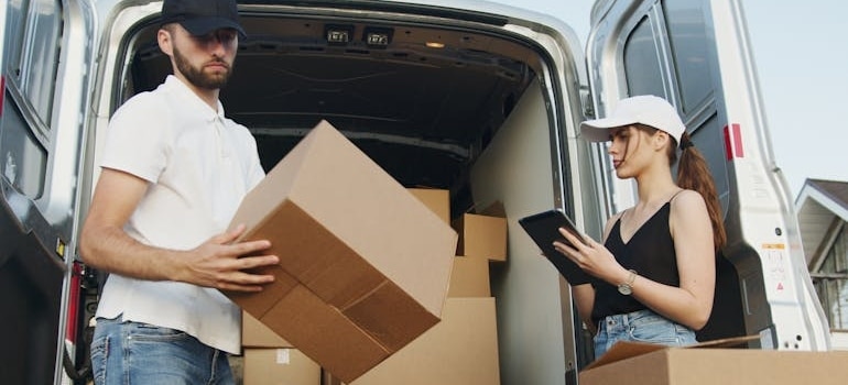 a man and a woman checking moving boxes, talking about how to load a moving truck when using a moving shuttle