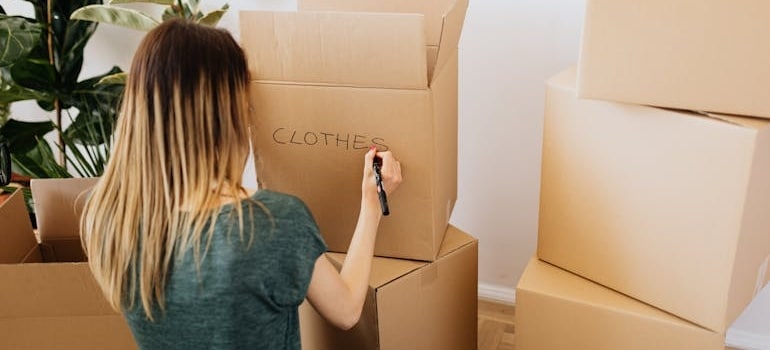 a woman labelling a box 'clothes'